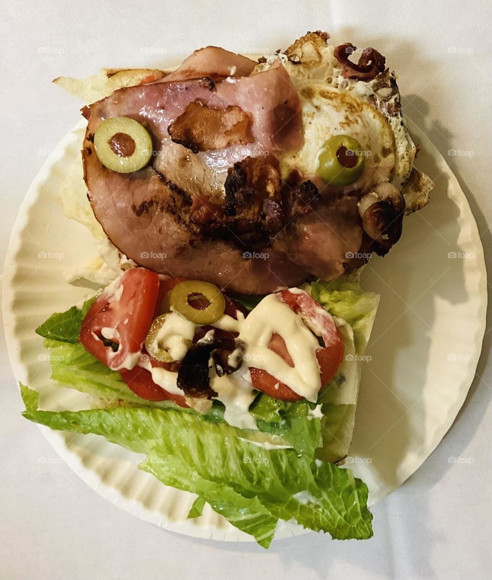 Sándwich chivito with tomate ,lettuce,ham ,1 egg olives ,mayonnaise ,bacon,olives chesse onion 