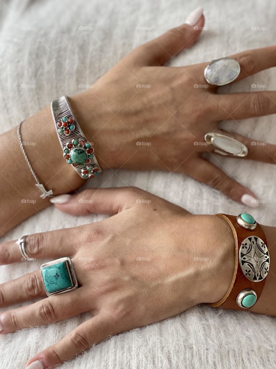 Woman’s hands wearing white nail polish manicure, silver and semi precious stones rings and bracelets 