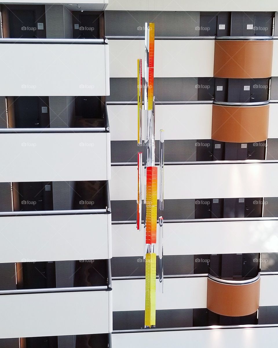 Modern hanging sculpture red yellow orange in open air hotel lobby tower