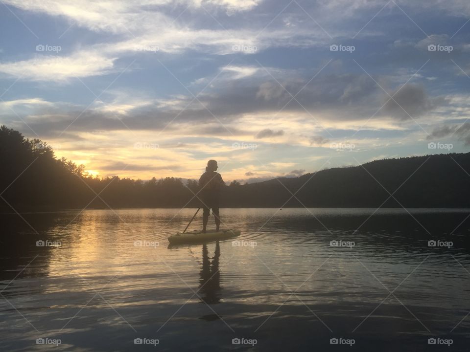 Paddle boarding at sunset on a small New England lake in the fall.