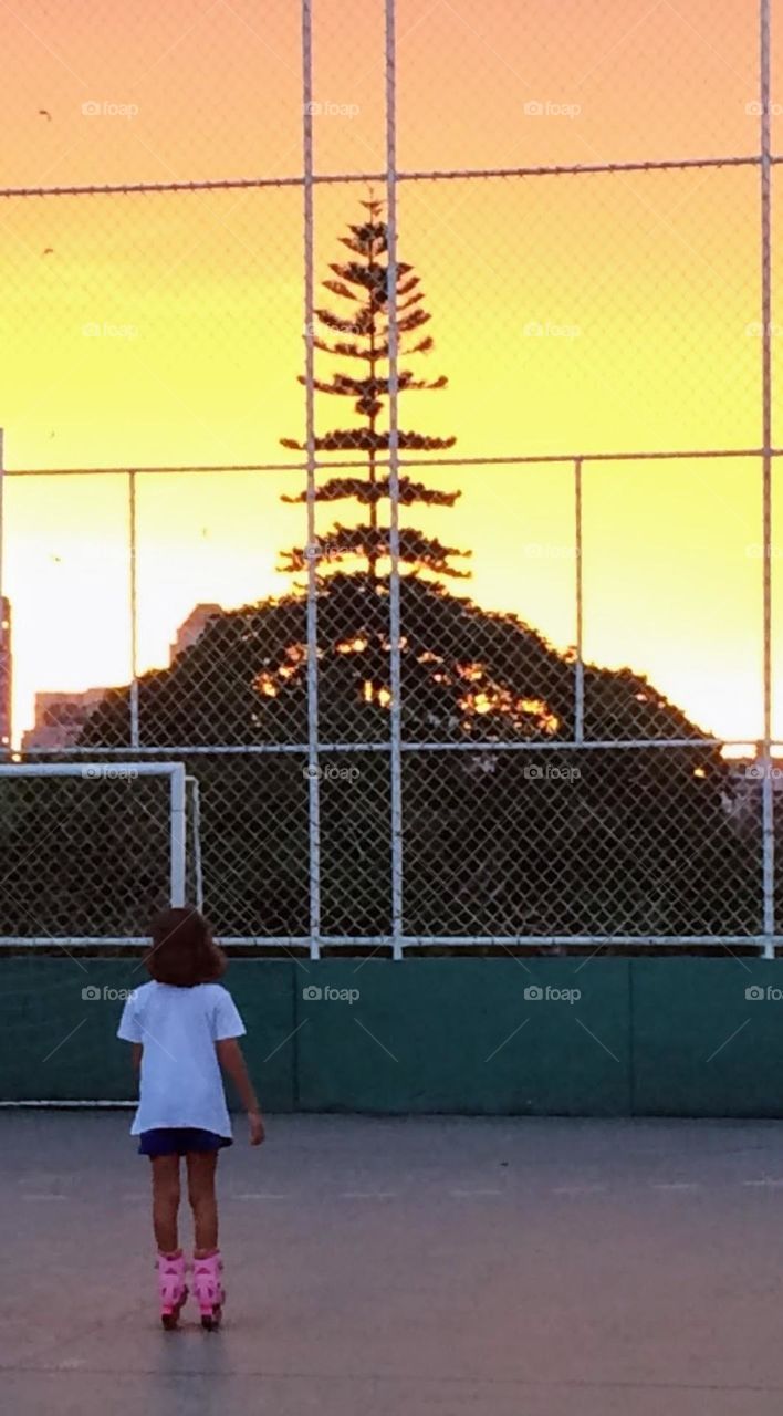 Child wearing roller skates looking at the sunset