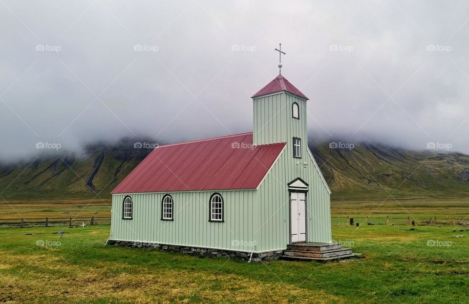 A small lght green church the morning fog