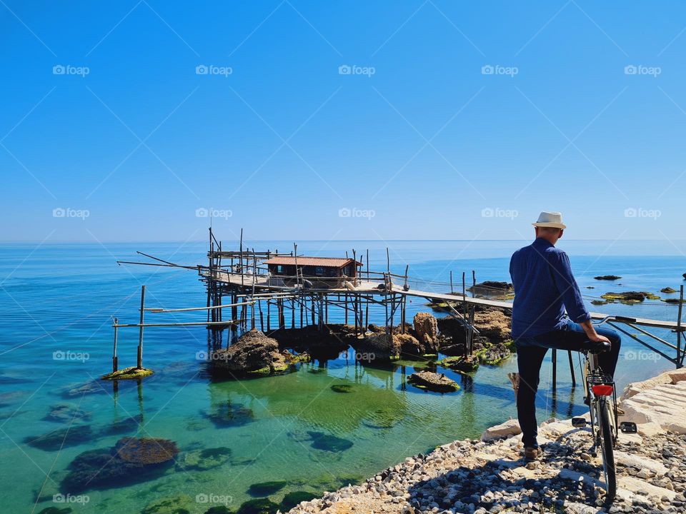 man from behind on bicycle looks at the overflow on the sea