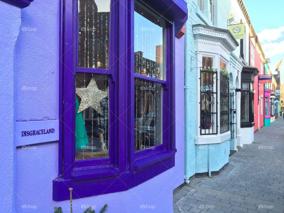 A window with a purple frame leads the eye along similar Windows down a shopping street in the UK. 