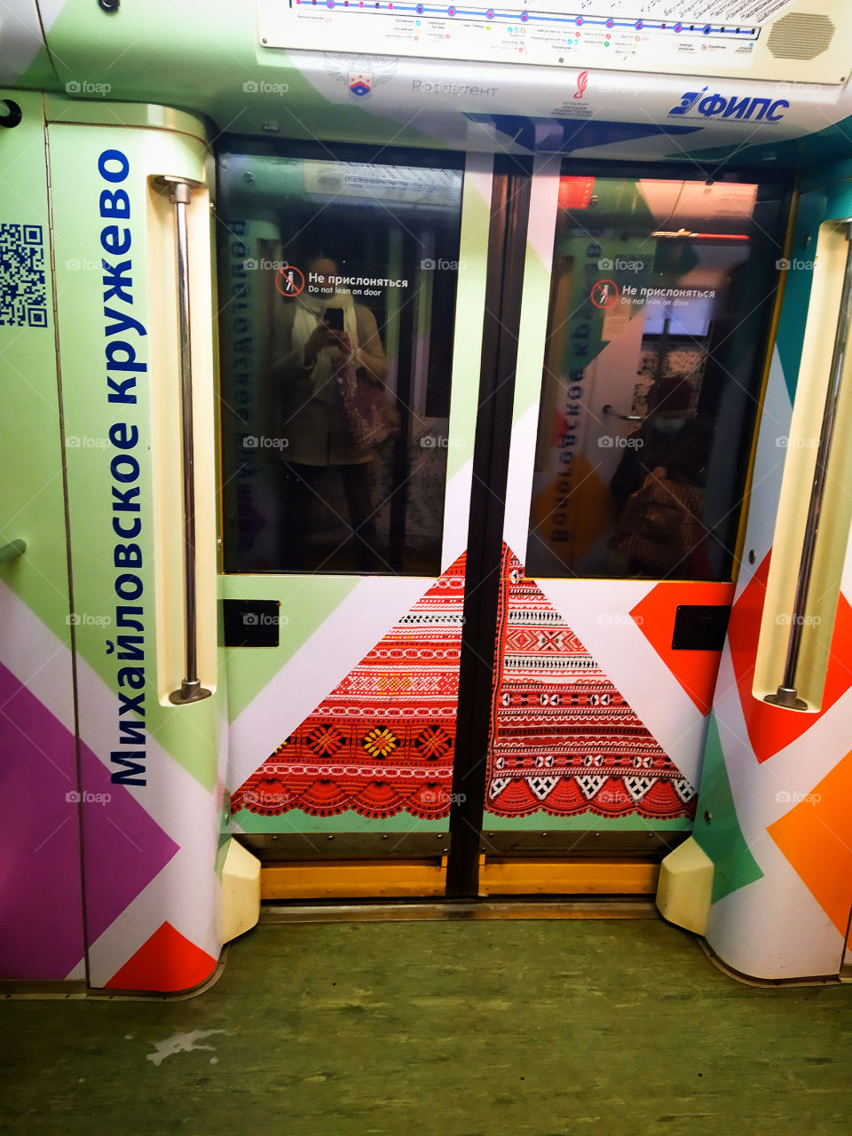 Moscow Metro.  Part of a train carriage decorated with colorful patterns.  The shadow in the glass