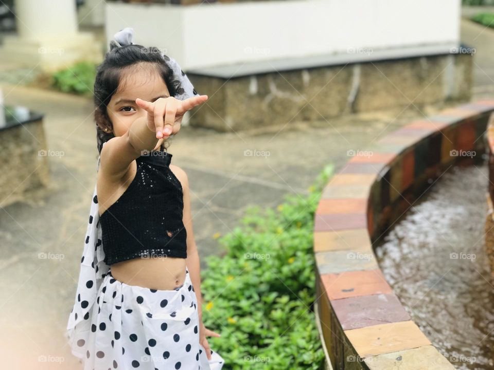 A beautiful girl wears  polka dots dress which is black and white combination along with polka dot hair band and making fun at outdoors 