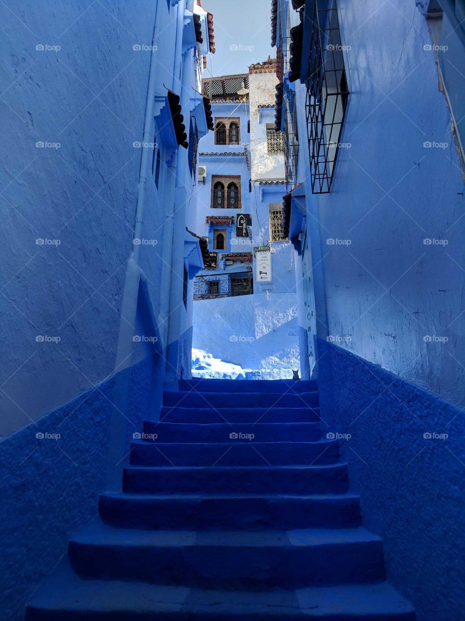 Blue street/alley in Chefchaouen (Blue City) in the mountains of Morocco, flowerboxes and stairs and windows