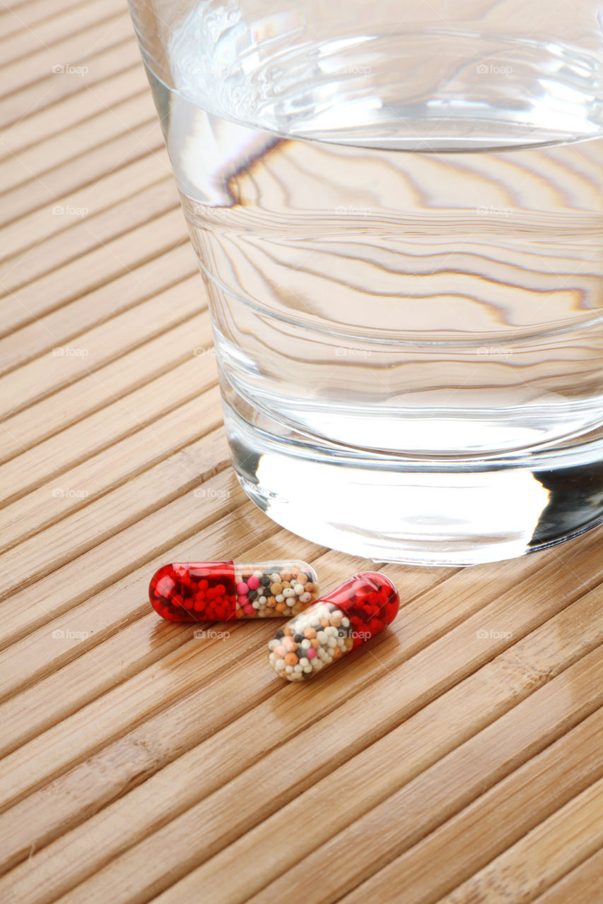 Medicine Capsules and glass on a wooden background