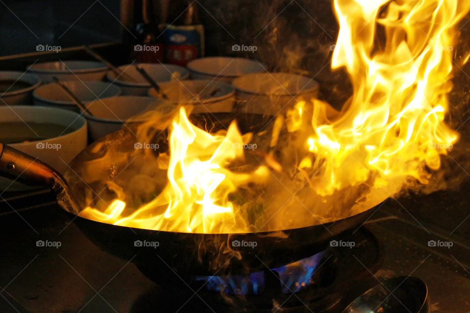 Fire in a wok  Asian pan, cooking at the kitchen