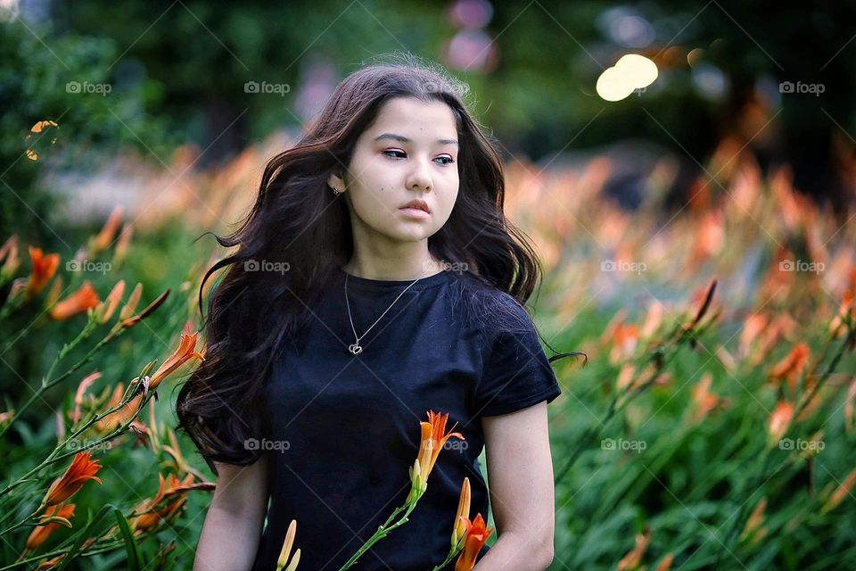 Asian girl with a beautiful long hair in a flowers field.
