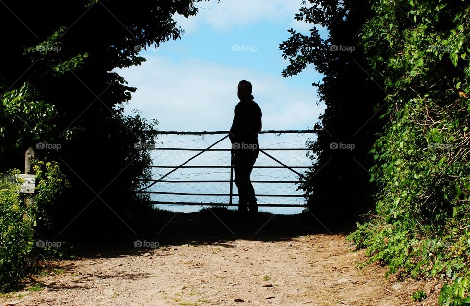 Man on farm silhouette by gate  