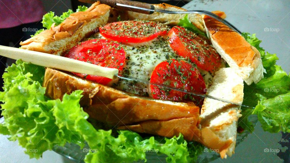 Lanche:  X Tudo no prato. Tomate, queijo, presunto, orégano, pão, alface, hambúrguer, ovo, bacon, linguiça e salsicha.