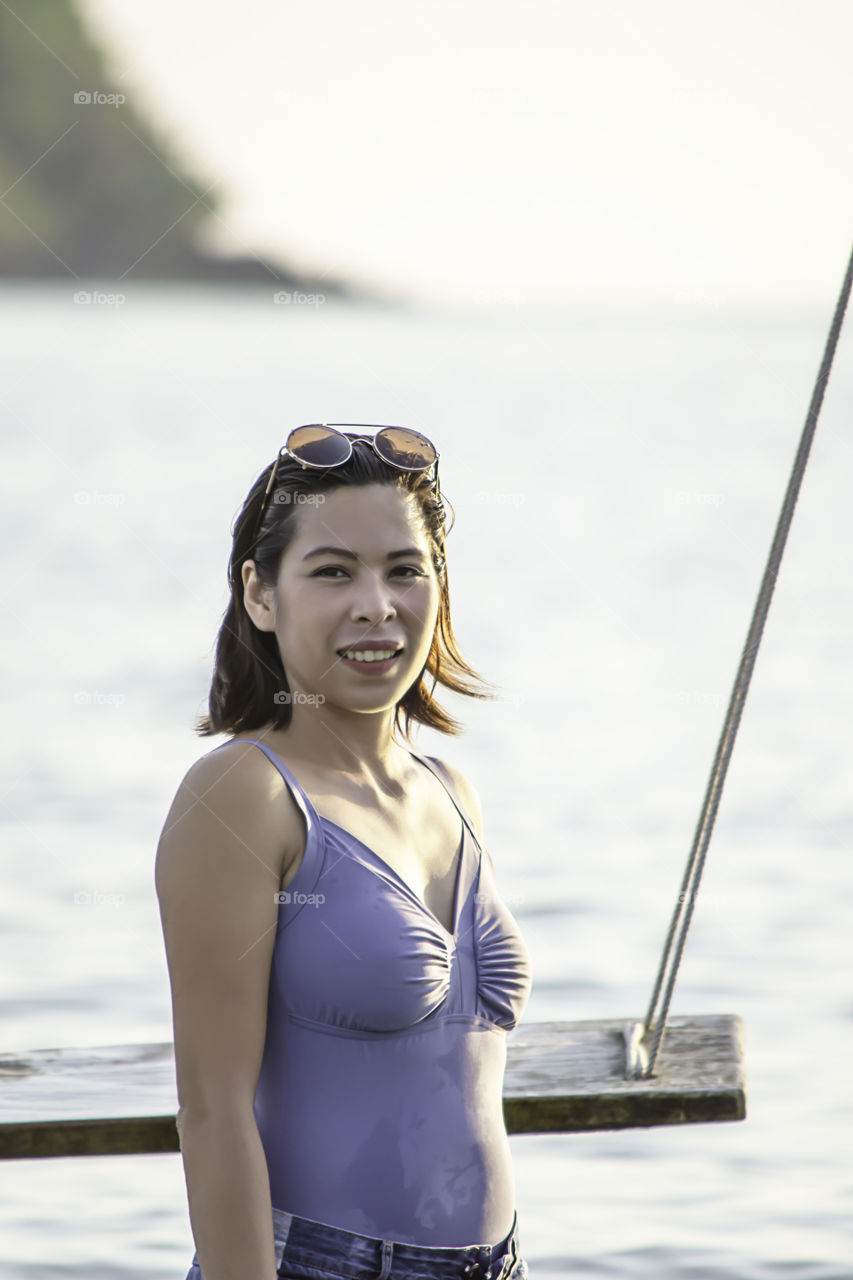 Portrait of Asian woman wearing a swimsuit background sea and sky