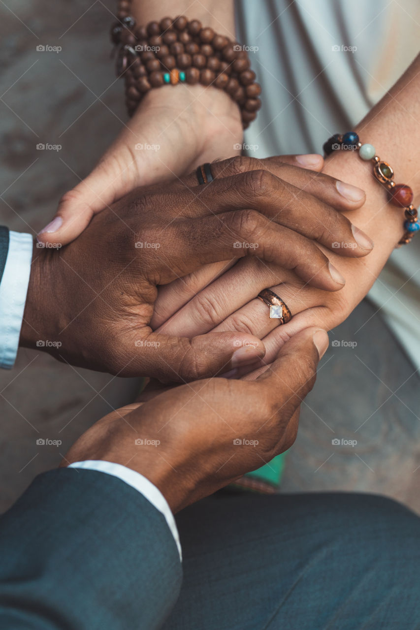 A biracial couple holds hands on their wedding day