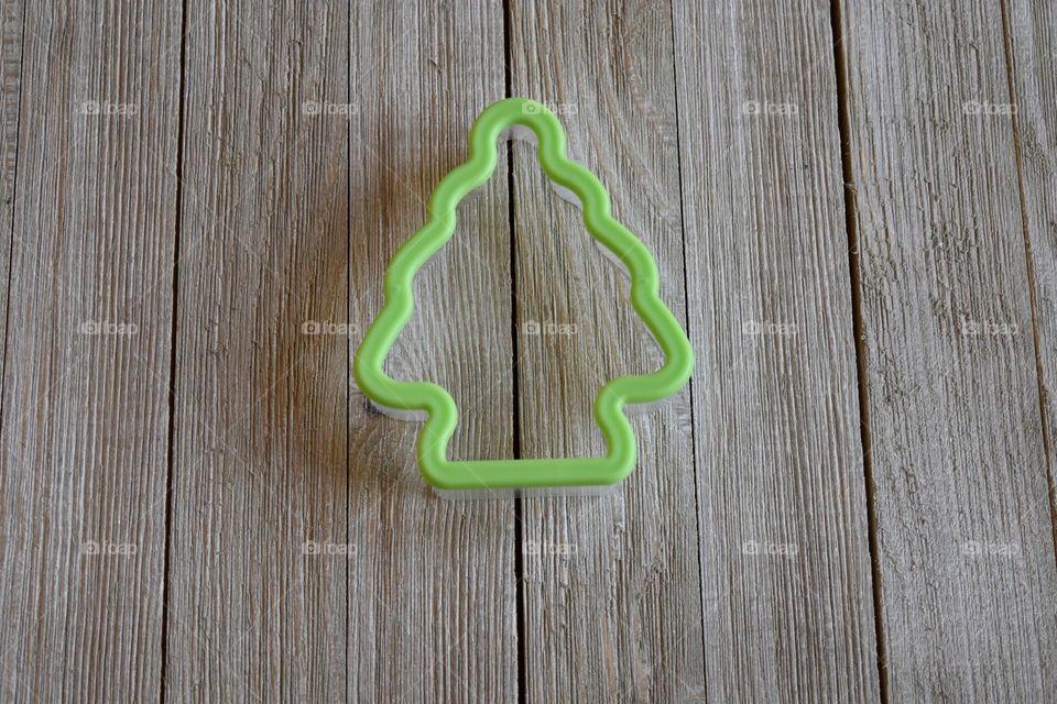 Cookie cutter in shape of a tree on wood background
