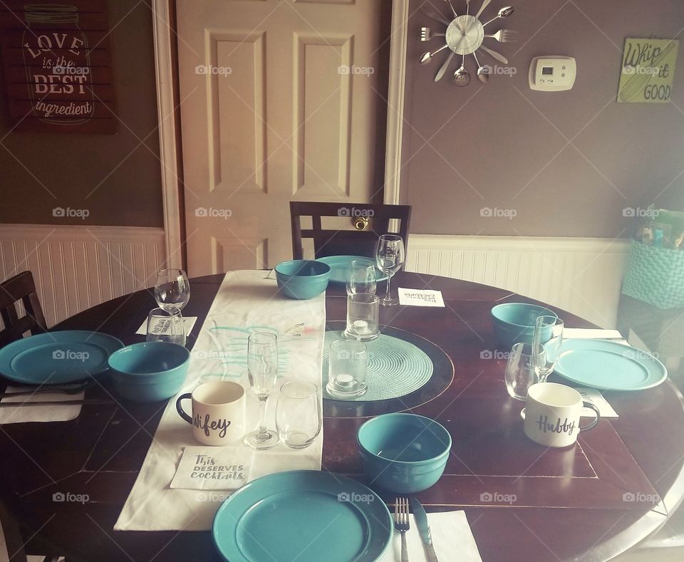 Flair of teal at the round dining table with refined settings, ready for the hungry family