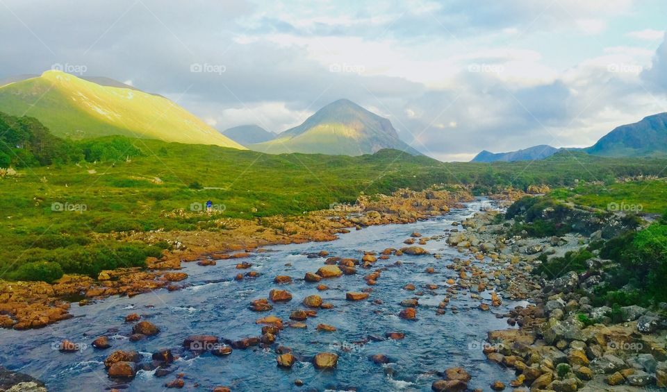 Beautiful creek against big mountains and blue sky background  in Carbost , Skye