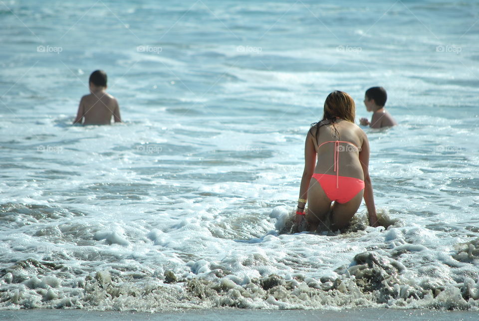 Woman in bikini playing with waves at the beach