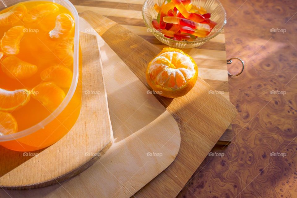 Delicious orange jelly with tangerine slices in a container and jelly worms.