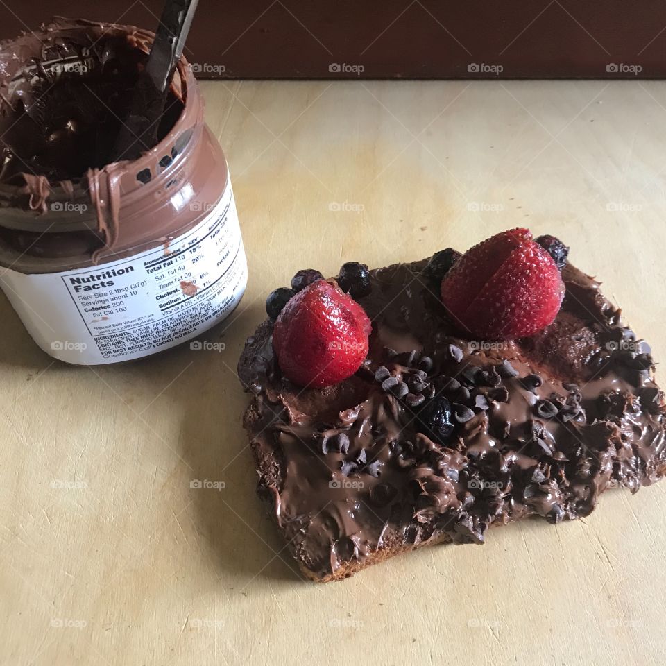 A very delicious and yummy Nutella sandwich with chocolate chips and strawberries Displayed on the cutting board in the kitchen being prepared for lunch . USA, America