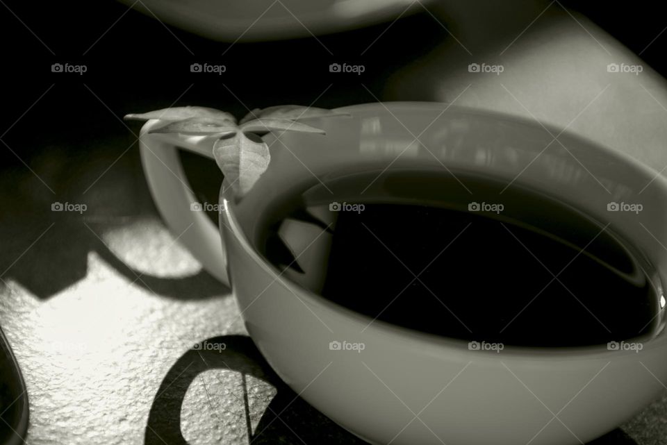 White cup with pomegranate tea on a black table.