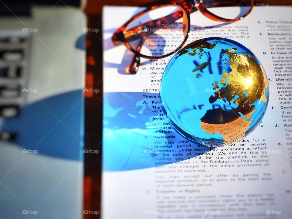 A desk with a world globe paperweight casting a blue shadow