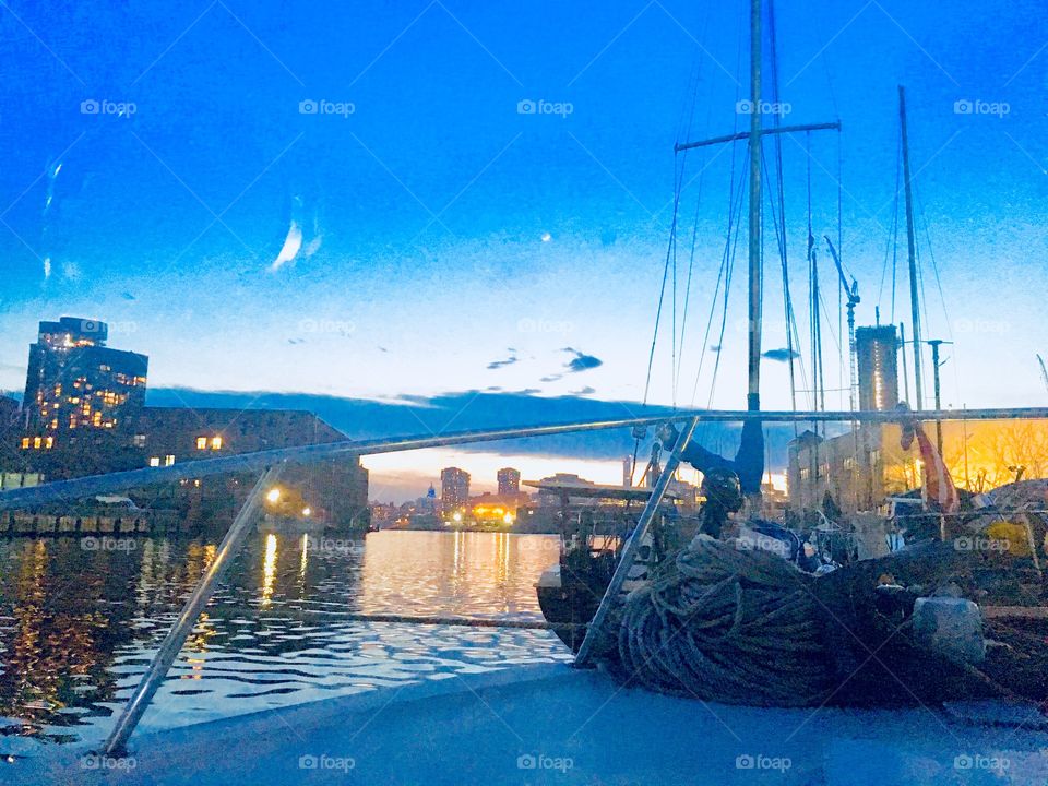 The glistening waves of the E River at Newtown Creek in LIC, Queens, NY with sailboats at sunset. In the distance you see the silhouette of Manhattan. The arched structure is not a bridge but a dark cloud formation. Photo 2018. Hypnotic Productions