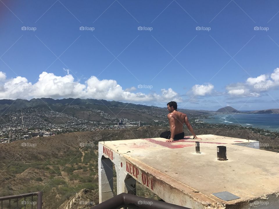 On the top of diamond head. Muscle guy sitting on roof top 