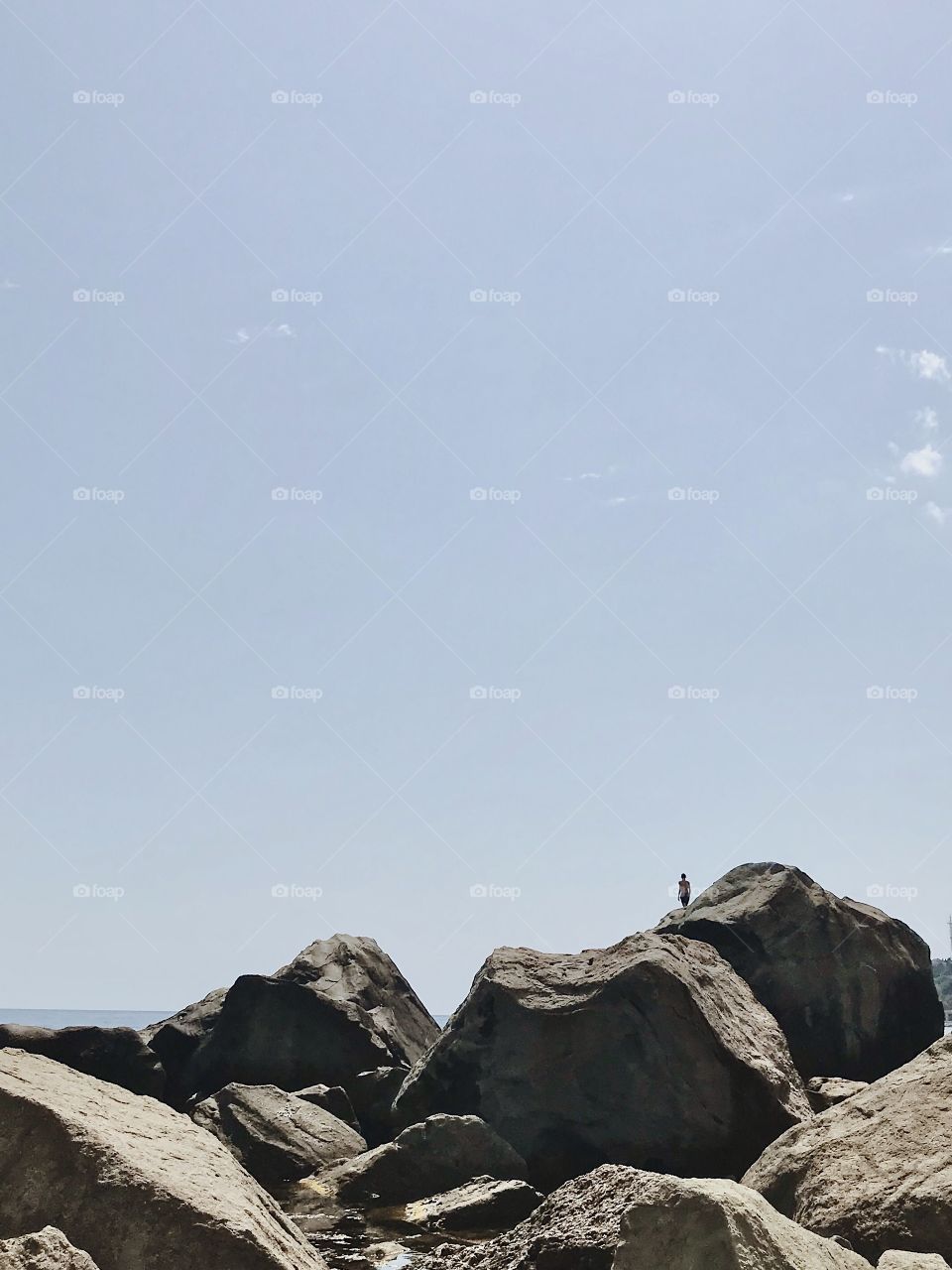 A man stands on a large stone