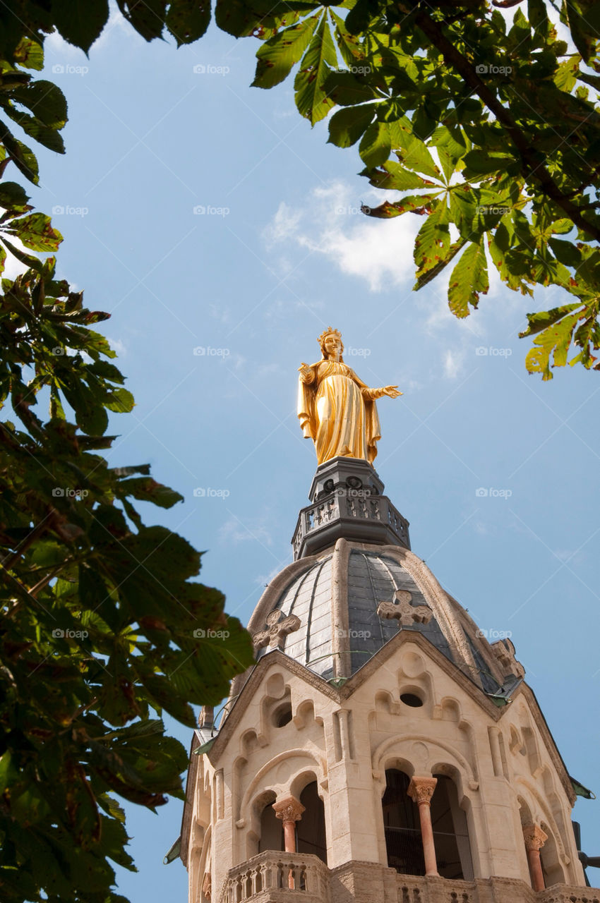 Gold statue on a steeple at a Catholic Church in Lyon France