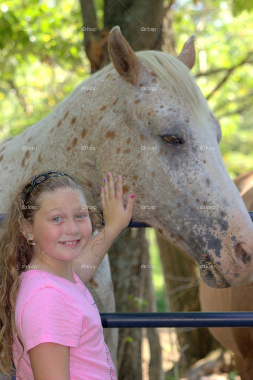 Smiling girl stroking horse