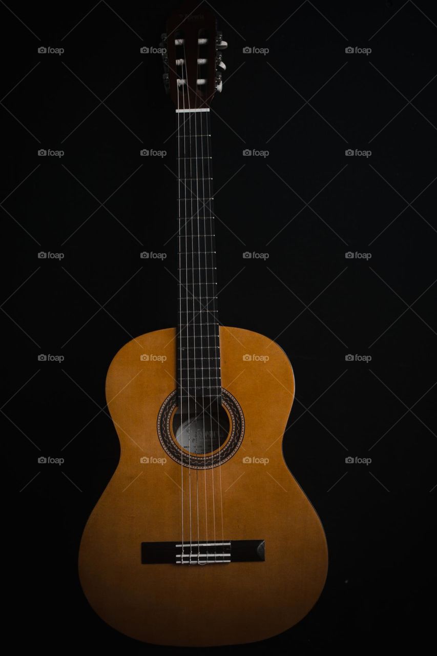 Wooden guitar with a black background