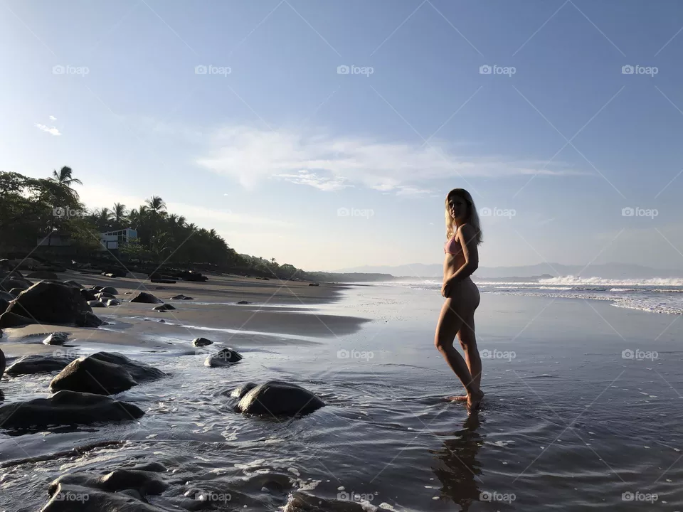 Early morning walk along private black sand beach in Costa Rica 