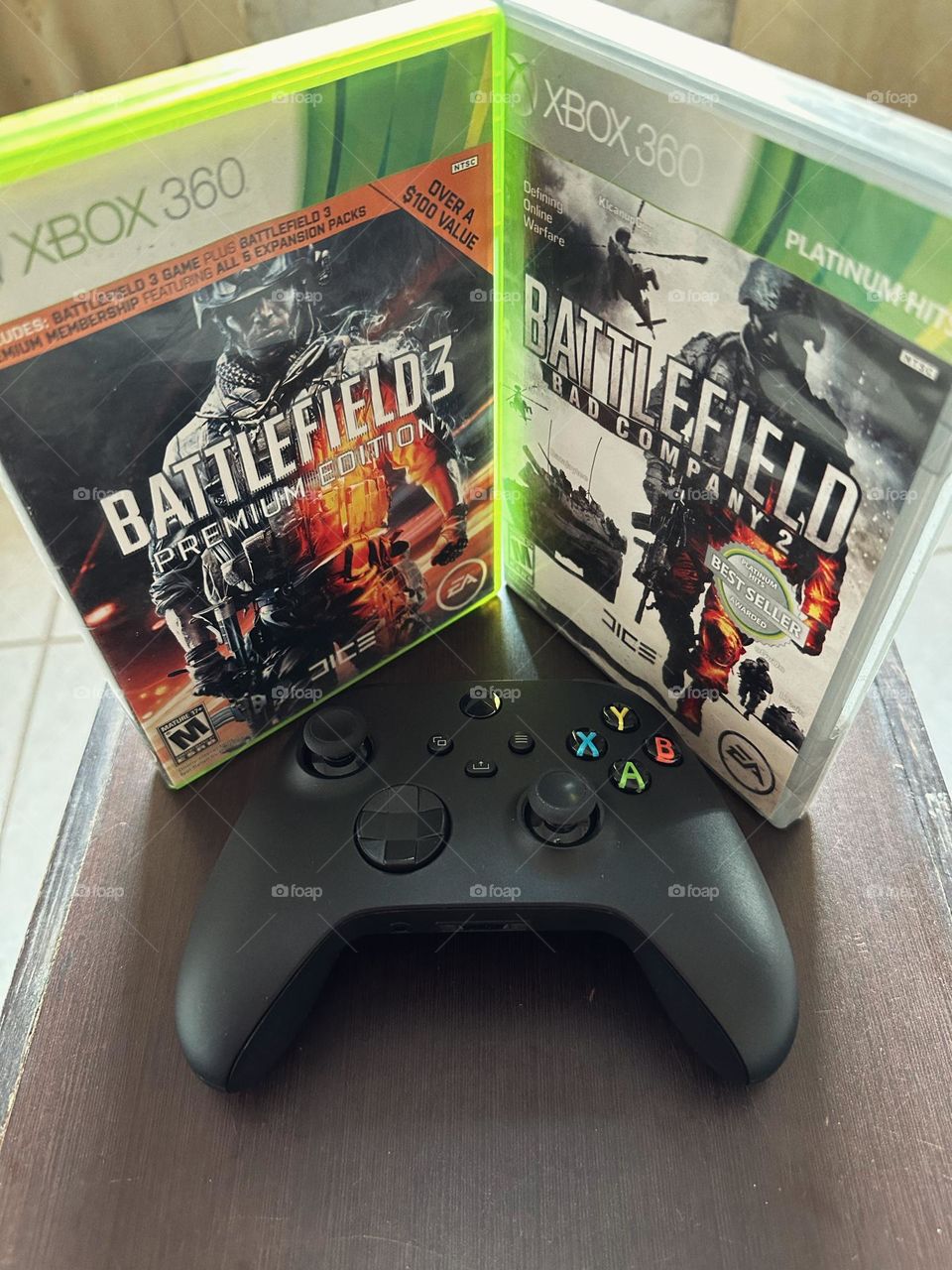 Battlefield boxes side by side with a Xbox controller in the middle of them with natural light.