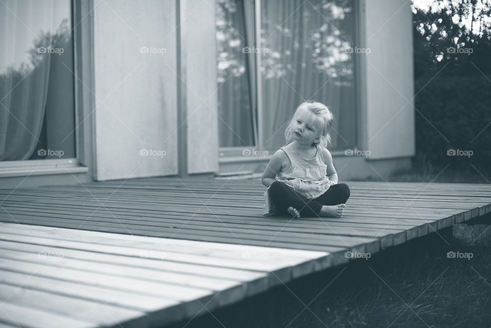 Little girl siting on outddor terrace in  yoga lotus pose