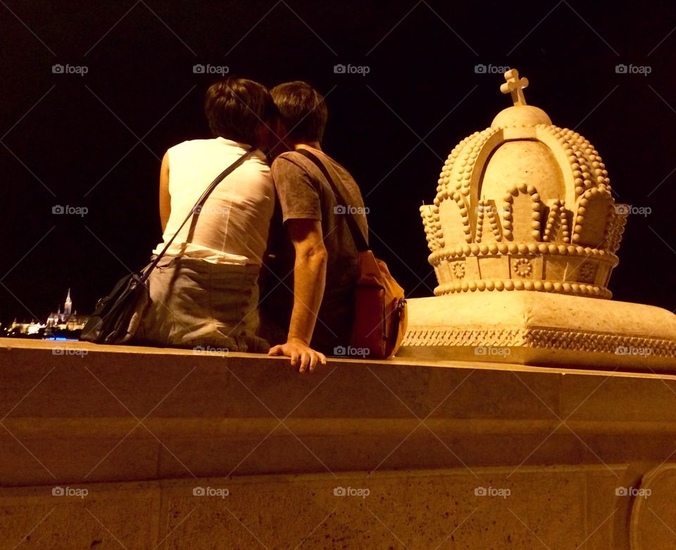 Walking over this bridge in Budapest I spotted this young couple sat with their legs dangling over the bridge in deep conversation .. I sneaked a photo of them from behind and love how the view of Parliament is just visible in the distance ๐