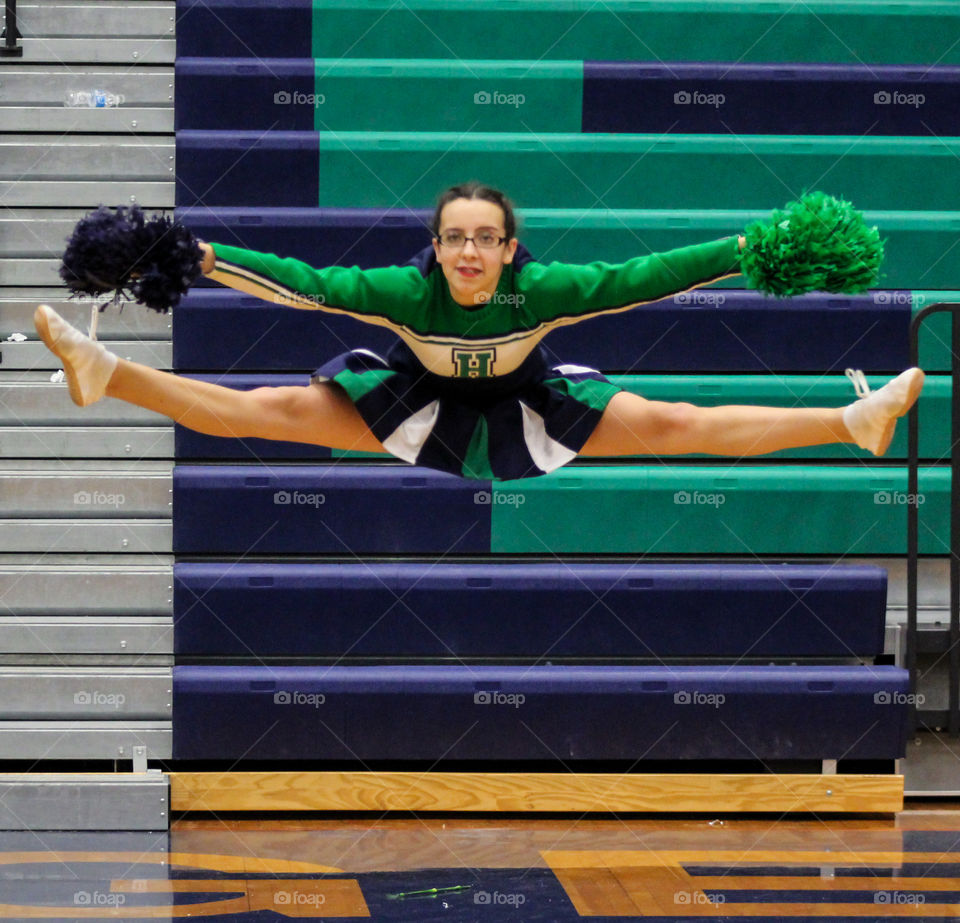 Flexible woman in mid-air with pom-pom