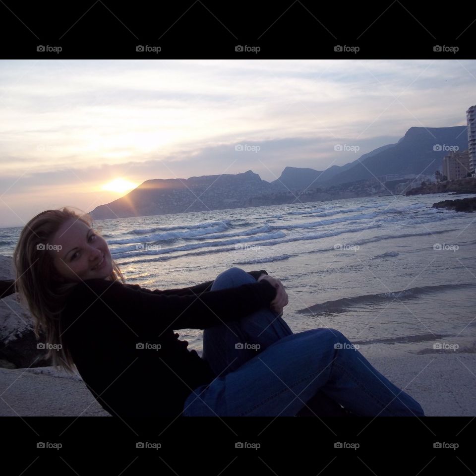 Woman sitting at beach during sunset