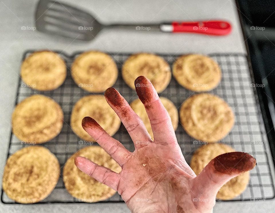 Woman’s hand covered in Cinnamon after making cookies, cinnamon covered hand from making Snickerdoodles at home, messy hands from baking at home, woman’s messy hands