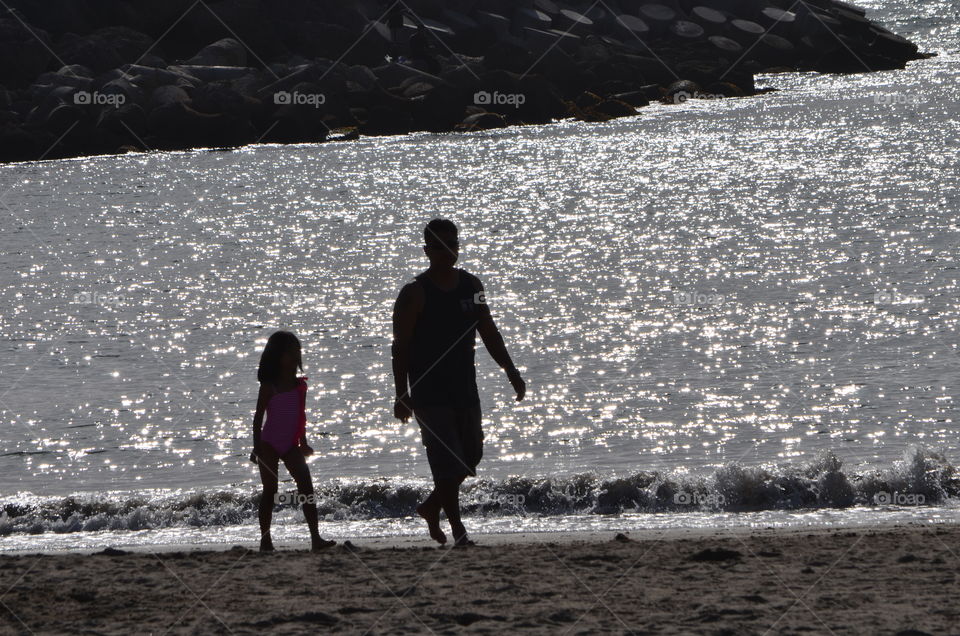 Father and daughter walking at the beach.