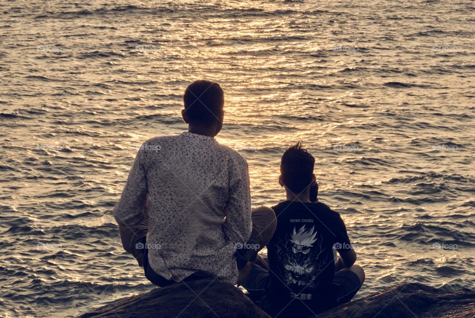 Two brothers watching the sun rise and enjoying the small moment in their life 