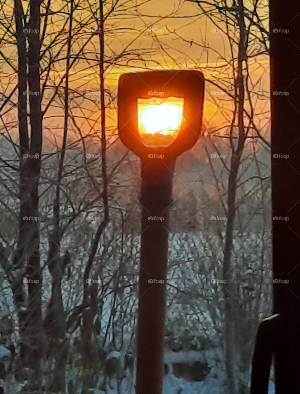 sunrise  in winter garden with sun peeking through the handle of a snow shovel