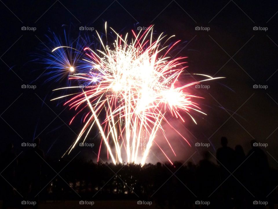 In France, the July 14 firework celebrates the national day and bring the French together around festivities. This photograph was taken in 2023 in a small town, the colors Blue White Red are those of the national flag.