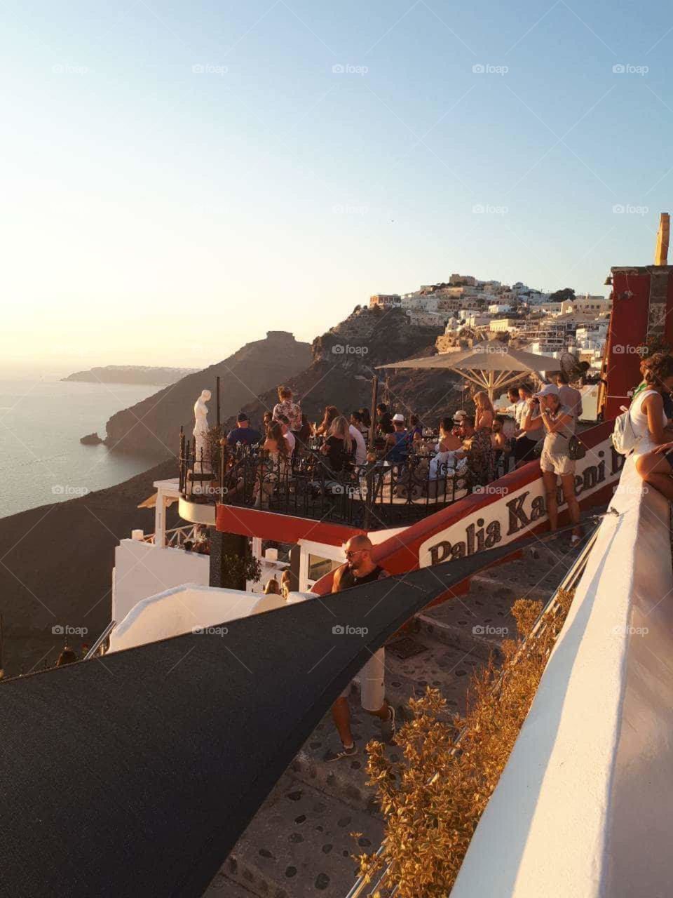 People  taking photographs and having fun at the beautiful island of Santorini. 
Amazing view of the sea. 
Careless times of vacation.