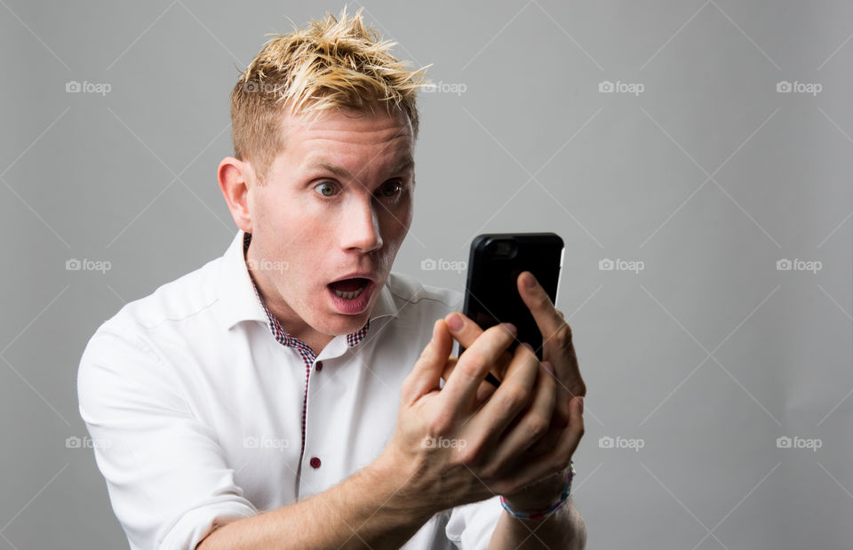 Surprise young man looking at mobile phone
