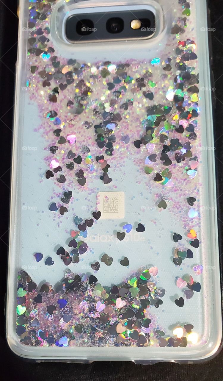 Technology today including cell phones. Samsung Android Galaxy S10e with sparkles in a clear case, sparkles floating in liquid cause movement.