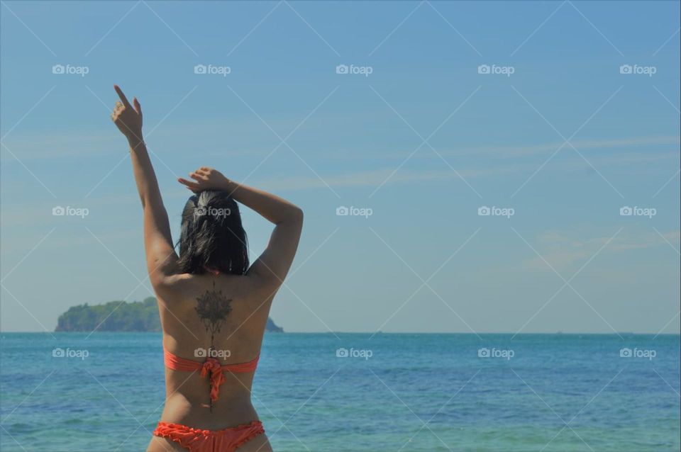 Girl wear bikini sits by the ocean in Sommer