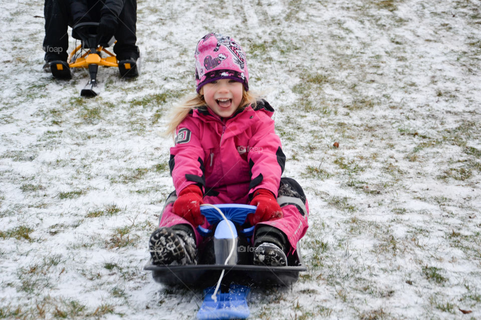 Young girl of five years old riding the sledge down a hill.