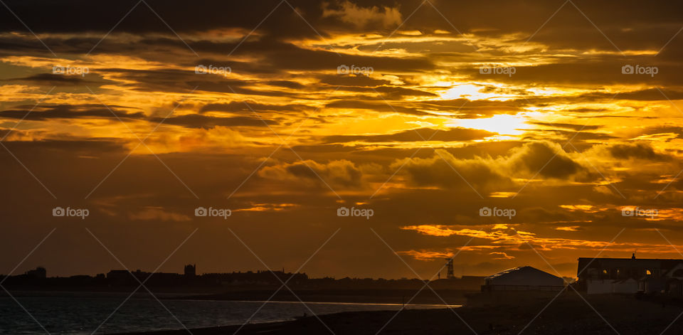 An orange and cloudy sunset sky dominates this image