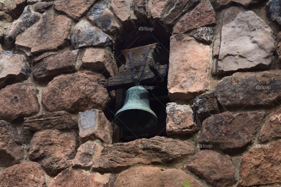 Old bell that has discolored is built into a stone edifice